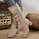 Beige knee-high boots worn with blue jeans on a neutral background