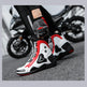 Motorcycle boots with red and black accents on a blurred motorcycle background