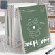 Notebook with a green cover featuring a bear illustration and text, placed on a surface.