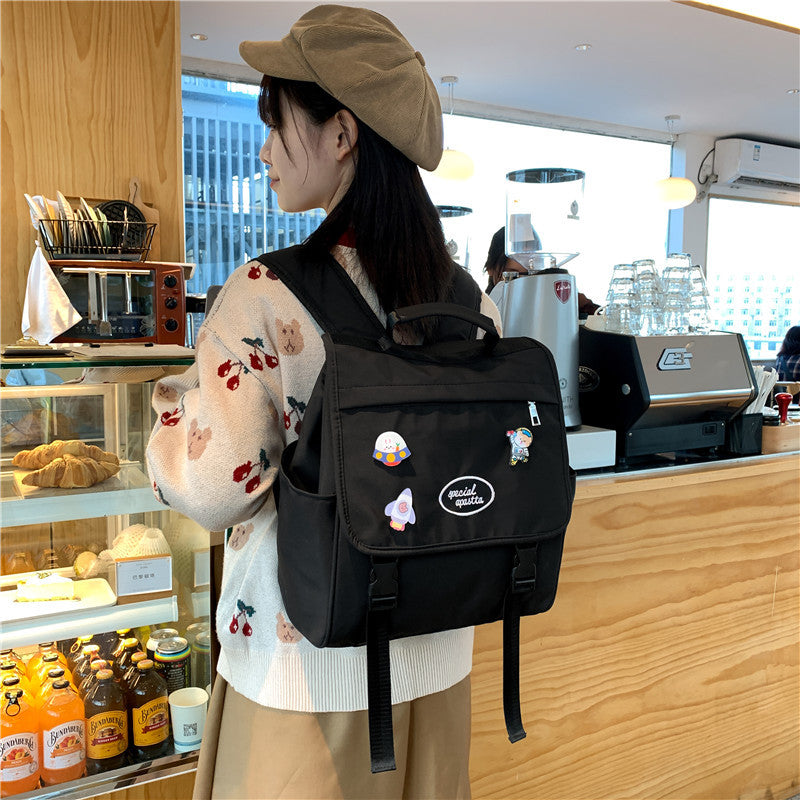 Person wearing a black backpack with cartoon characters in a cafe setting