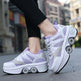 Person wearing white and purple sneakers with roller wheels on a city street.