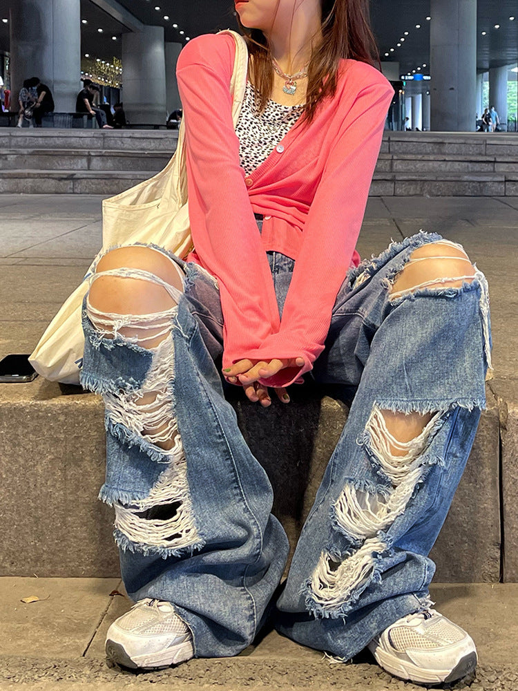 Person wearing ripped jeans and a pink top sitting on steps.