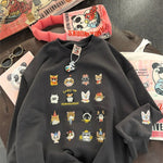 Black sweatshirt with cat illustrations on a table with books and sunglasses.