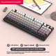 Mechanical keyboard with RGB lighting on a desk with a tablet and smartphone in the background.