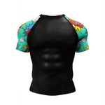 A men's short-sleeve athletic rash guard with a black torso and colorful comic-book style sleeves. The sleeves feature a turquoise background with yellow, orange, and white comic-style text and graphic elements.