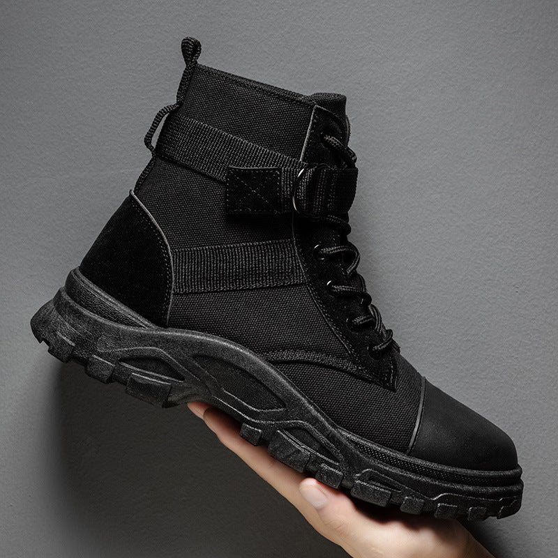 Black tactical boot held by a hand against a gray background
