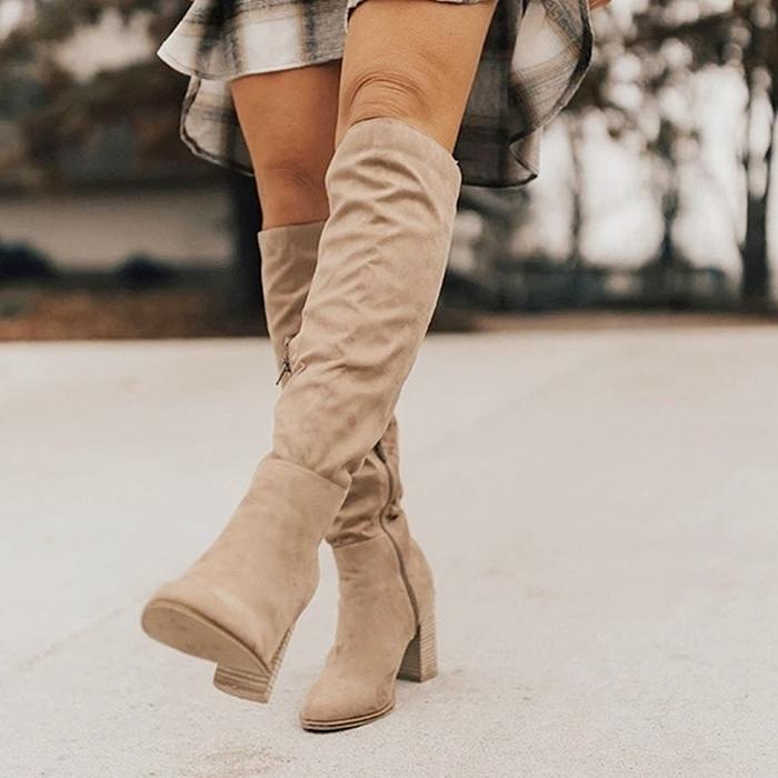 Beige knee-high boots worn with a plaid skirt on a blurred outdoor background