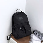 Black backpack on a wooden surface with a white wall background