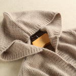 Close-up of a beige sweater with a mannequin head inside on a light beige background