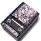 Floral patterned tie set with tie clip and pocket square in a black box on a white background