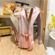 Pink backpack with bunny ears on a wooden surface