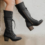 Black lace-up boots on a neutral background