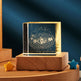Transparent block with solar system diagram on a wooden base against a dark blue background