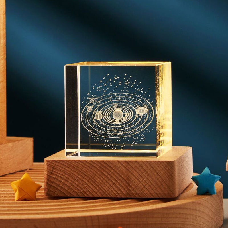 Transparent block with solar system diagram on a wooden base against a dark blue background