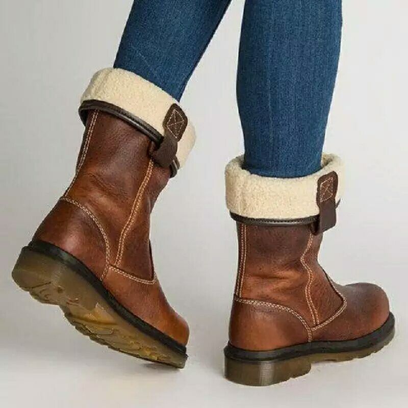 Brown winter boots with white fur lining worn with blue jeans on a light gray background