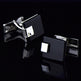 Black and silver square cufflinks on a reflective black surface