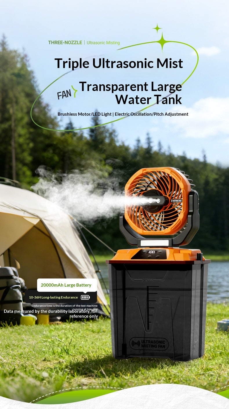 A portable ultrasonic mist fan and water tank set shown outdoors near a tent and lake, with mist spraying from the fan. The product has a black body with orange accents and a transparent tank.