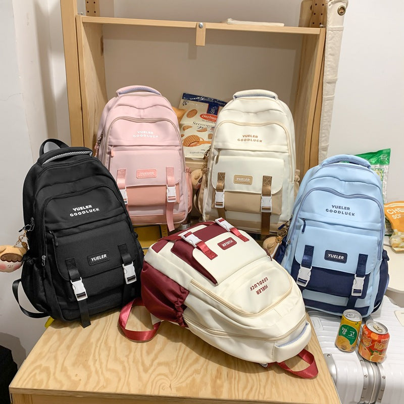 Five backpacks in various colors on a wooden shelf. Large Capacity Nylon Backpack – Cartoon Cute Style | 10 Colours