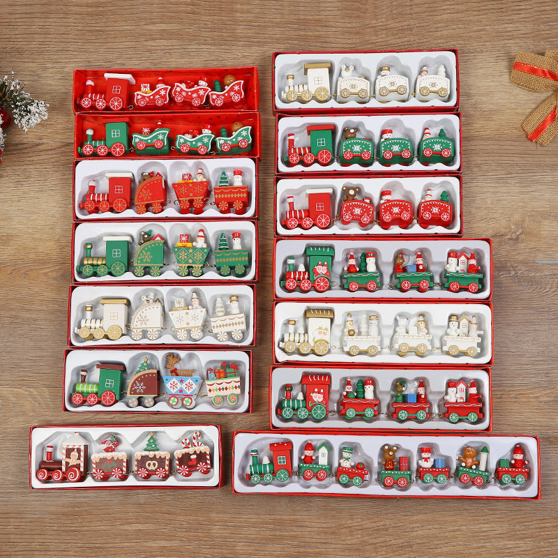 A set of Christmas-themed miniature toy trains and locomotives displayed in multiple red and white gift boxes on a wooden tabletop. The trains feature festive holiday designs including Santa Claus, Christmas trees, snowflakes, and red-and-green holiday patterns.