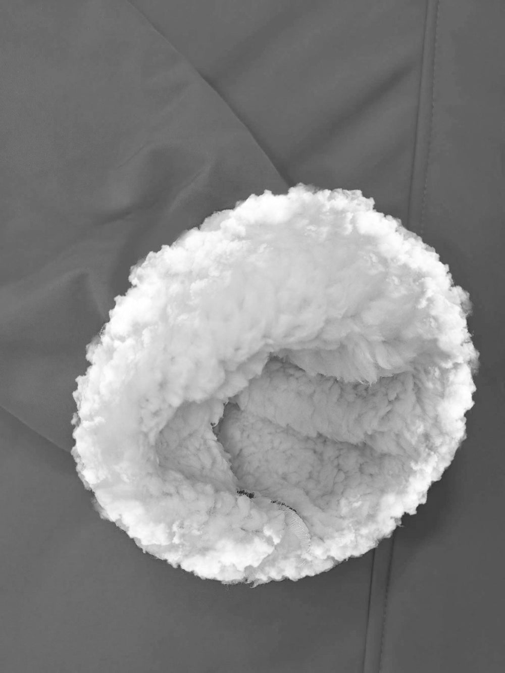 Close-up of a white sherpa fleece-lined cuff on a dark gray garment.