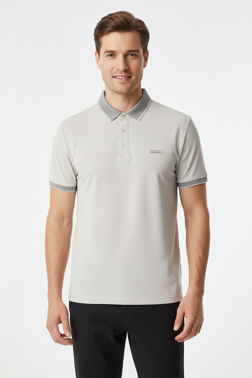 A man wearing a light gray short-sleeve polo shirt with a darker gray collar and sleeve trim, paired with black pants, photographed against a plain light gray studio background.