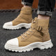 Tan tactical boots with white soles worn by a person on a dark surface