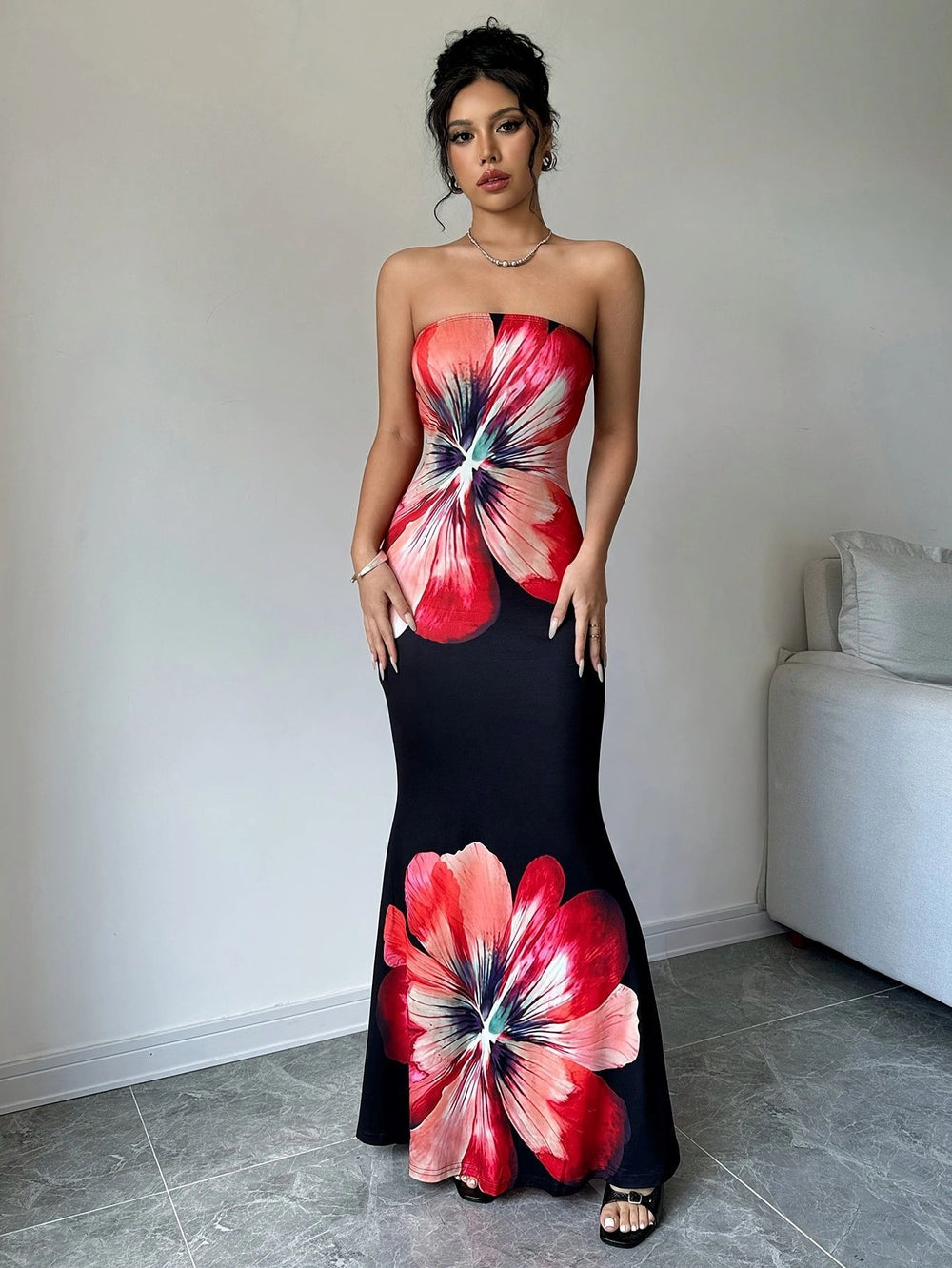 Woman wearing a strapless dress with large floral patterns in a minimal room.