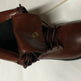 Brown leather boot with a button on a white background