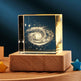 Glass block with galaxy design on a wooden base against a dark background