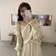 Woman taking a mirror selfie wearing a light-colored sweater and skirt in a minimalistic room.