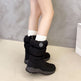 Black winter boots worn with white socks on a neutral background