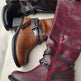 Three boots in black, brown, and burgundy with decorative straps and zippers on a light background.