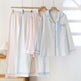 Pastel striped pajama set on hangers against a white background