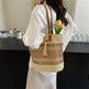 Person holding a woven handbag with a tassel and flowers, standing in a room.