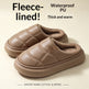 A pair of taupe brown fleece-lined slipper slippers with quilted stitching and a soft inner lining, shown on a light beige background with promotional text overlays.