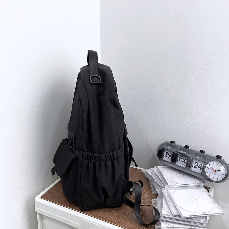 Black backpack on a wooden surface with a white wall background