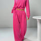Person wearing a bright pink off-shoulder top and matching pants on a plain background
