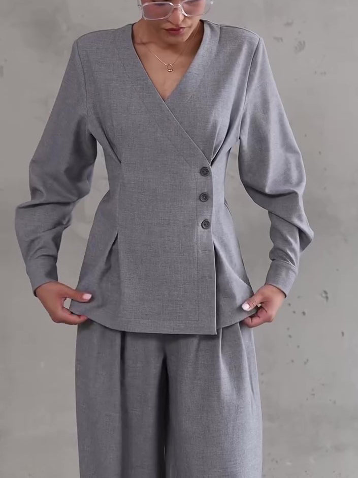 Person wearing a gray suit with a plain background