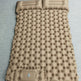 A tan inflatable sleeping pad with a quilted bubble pattern and two integrated headrests, laid flat on a gray textured surface.