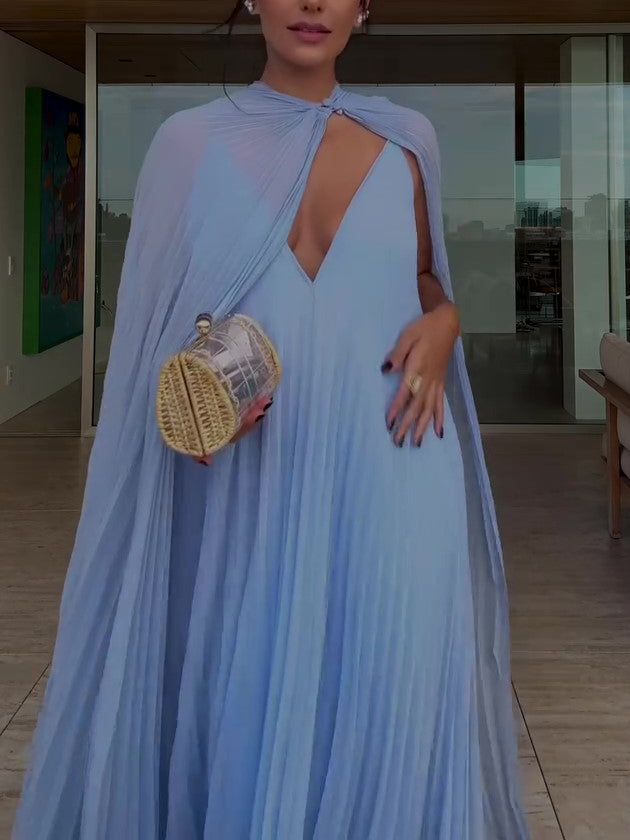 Woman in a light blue dress holding a woven handbag indoors.