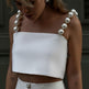 Woman wearing a white strapless top with pearl-like shoulder details.