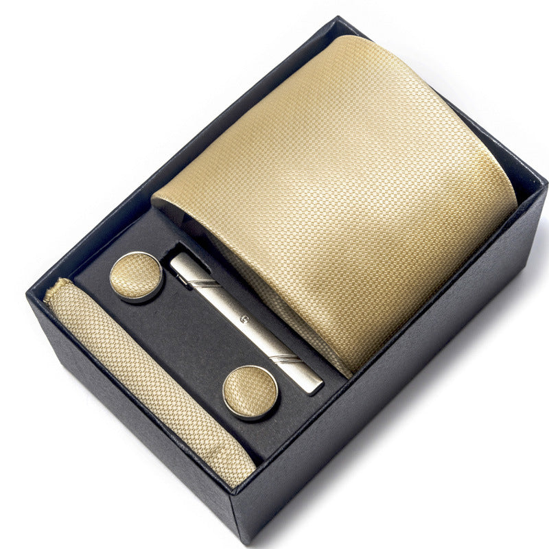 Gold tie set with tie, pocket square, and cufflinks in a black box on a white background