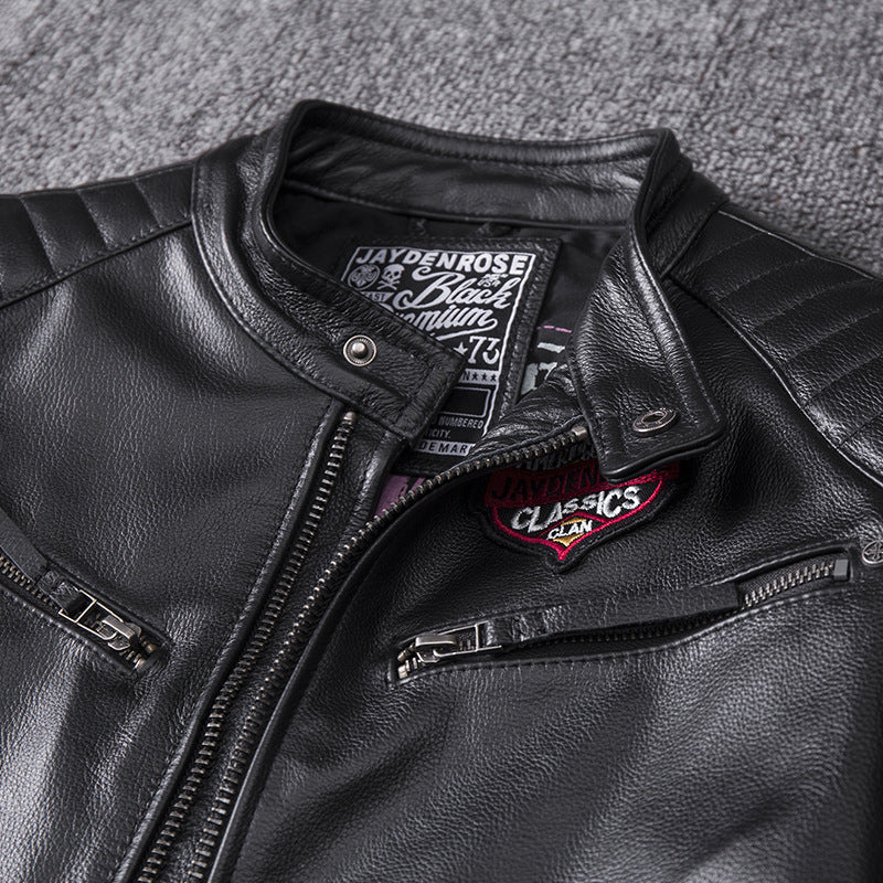 Close-up of a black leather jacket with brand patches on a textured gray background