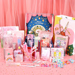 Assorted stationery items on a pink surface with a Christmas-themed card in the background.