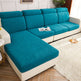 A sectional sofa with bright teal textured seat and back cushions and cream-colored arms, base, and side panels, shown in a styled living room with a white shag rug, wood floor, and small side table.