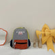 Children's backpack with colorful design on a white surface with decorative items.