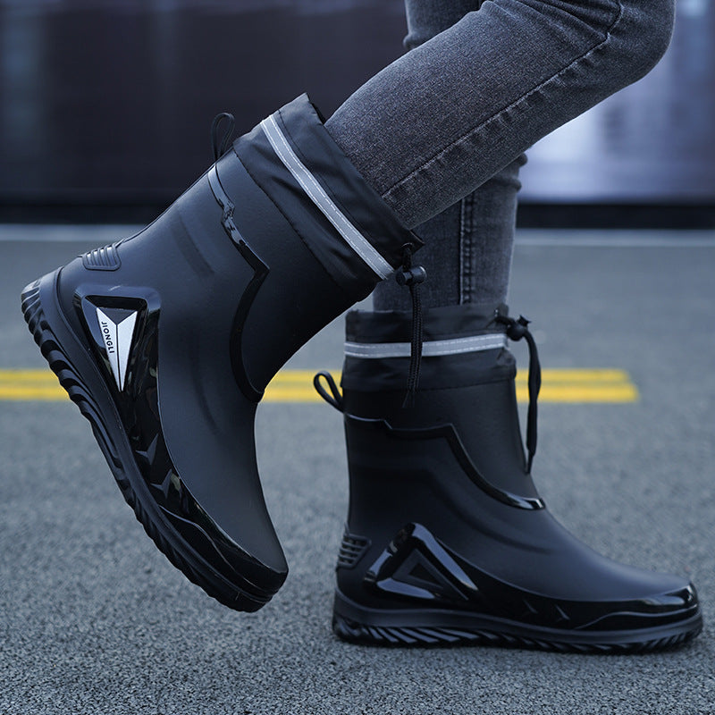 Black rubber boots with white stripes worn by a person on a blurred street background