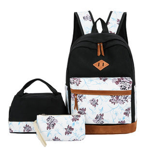 Black backpack with floral design, matching pouch, and small bag on a white background