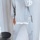 Person wearing a gray tracksuit with white accents in a minimalistic room.