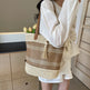 Person holding a woven bag with flowers, wearing a white outfit indoors.